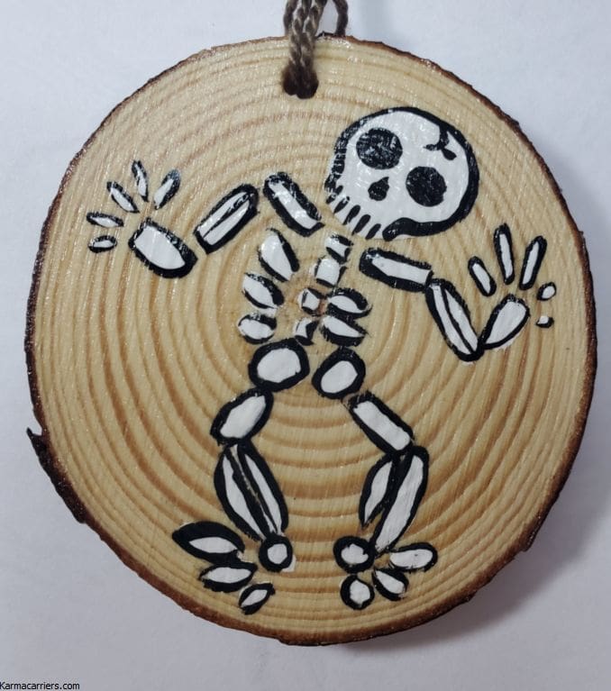 A wooden disc with a skeleton painted on it.