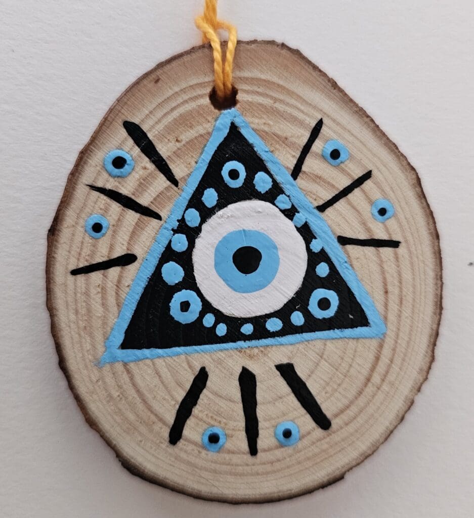 A wooden slice with an evil eye painted on it.