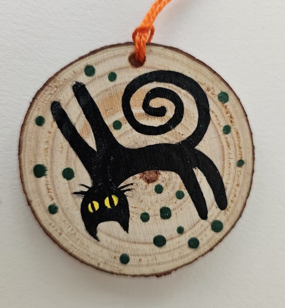 A wooden disc with a black cat on it