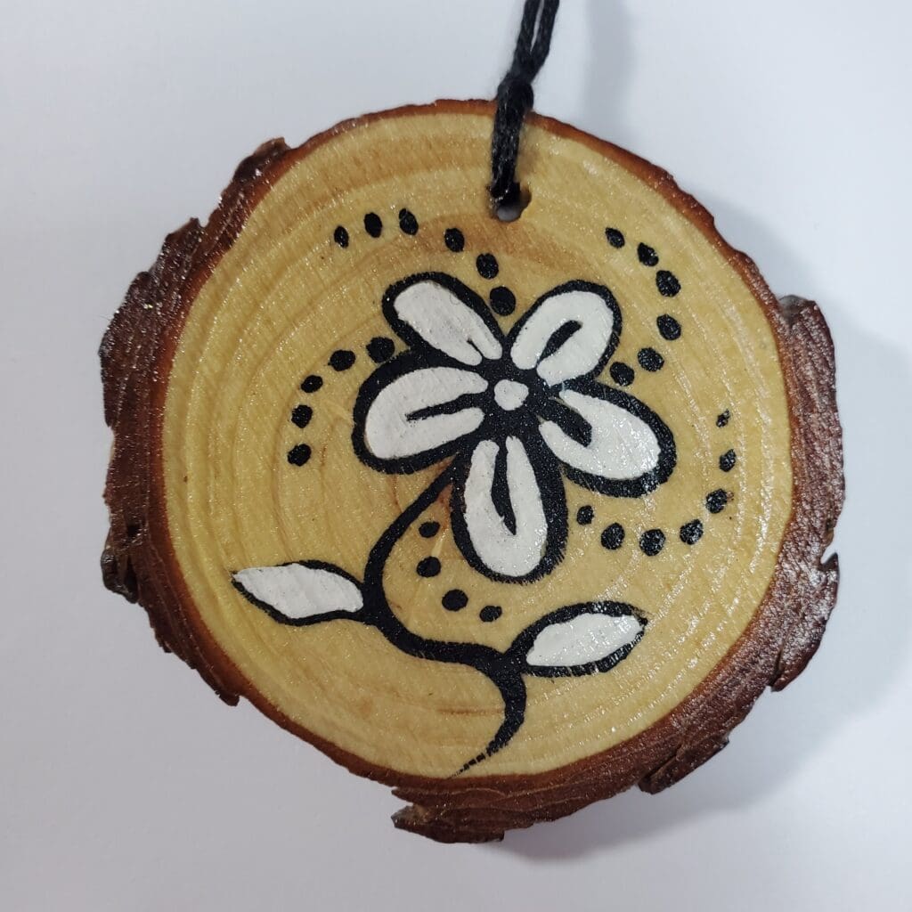 A wooden disc with a flower painted on it.