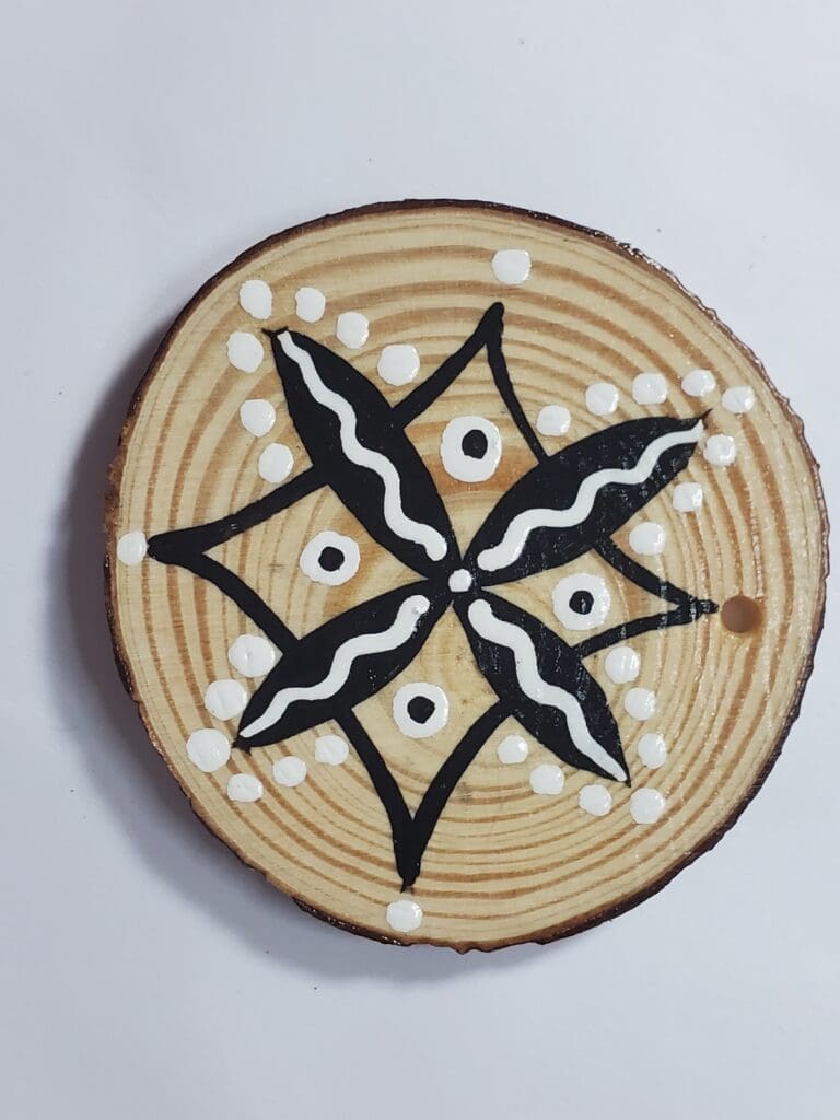 A wooden plate with black and white designs on it.