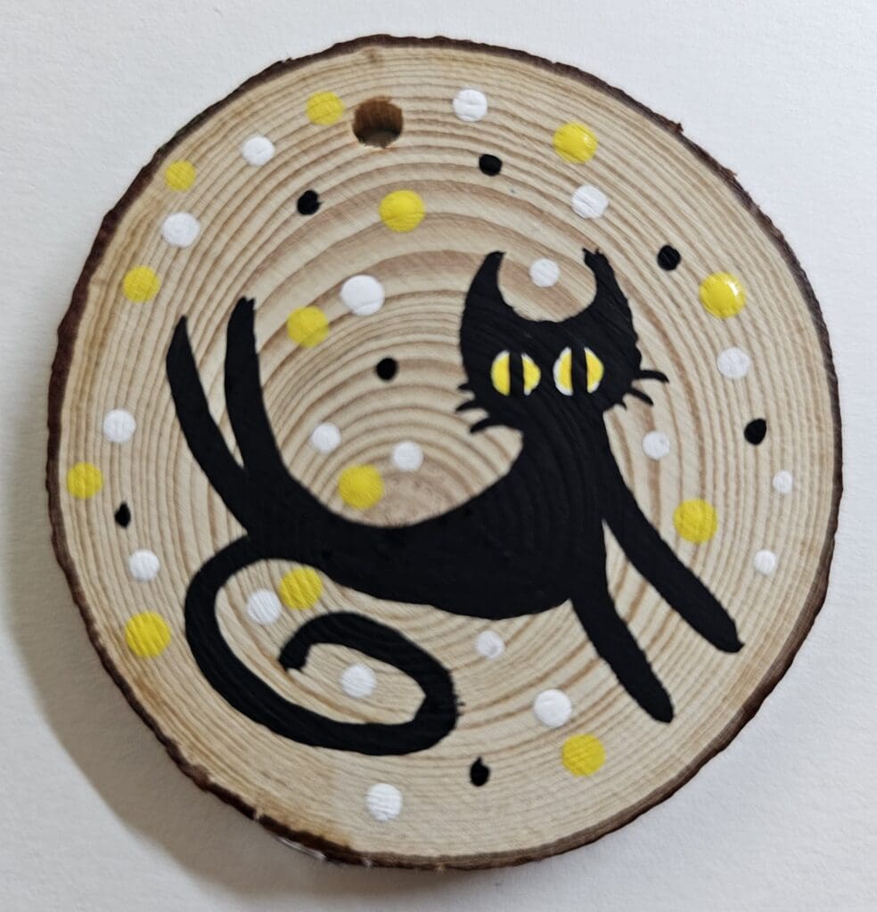 A black cat with yellow eyes on a wooden disc.