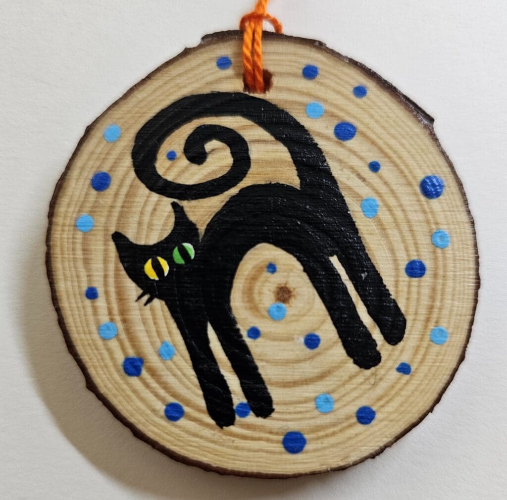 A black cat on a wooden disc with blue dots.