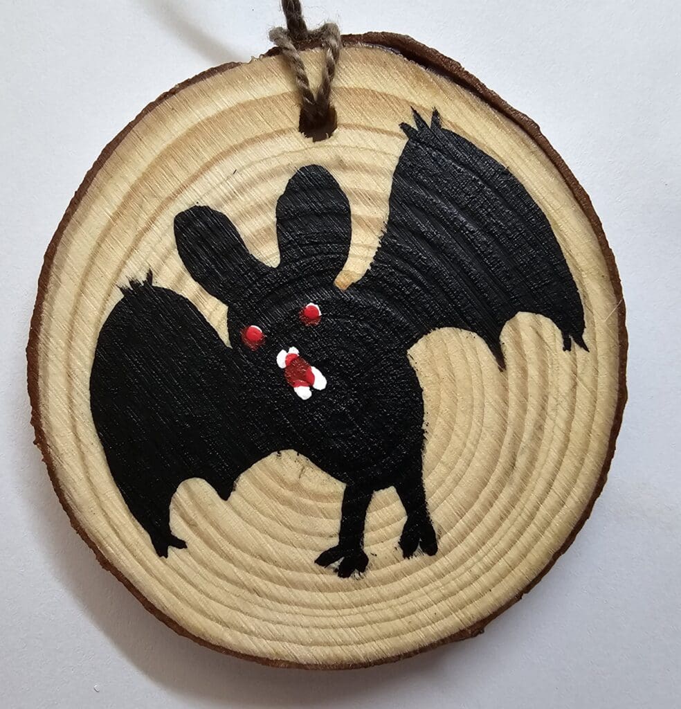 A bat ornament hanging on the side of a tree.