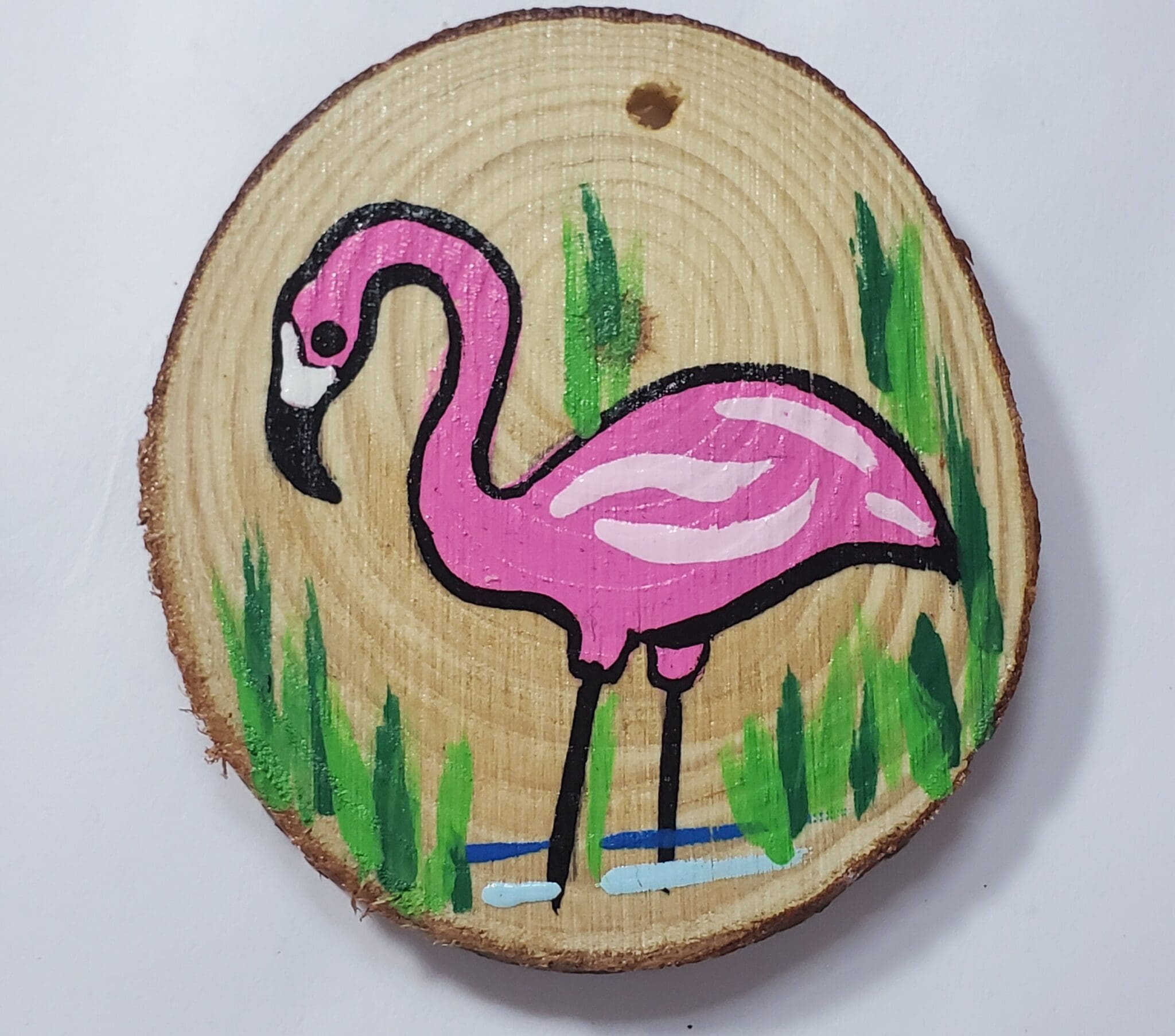 A pink flamingo painted on wood slice.