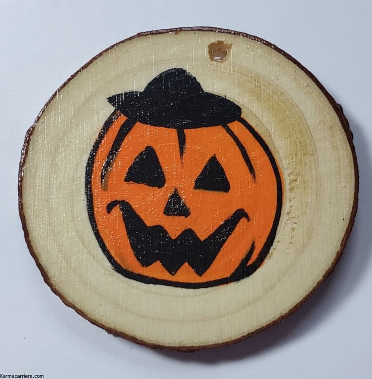 A wooden slice with an orange pumpkin on it.