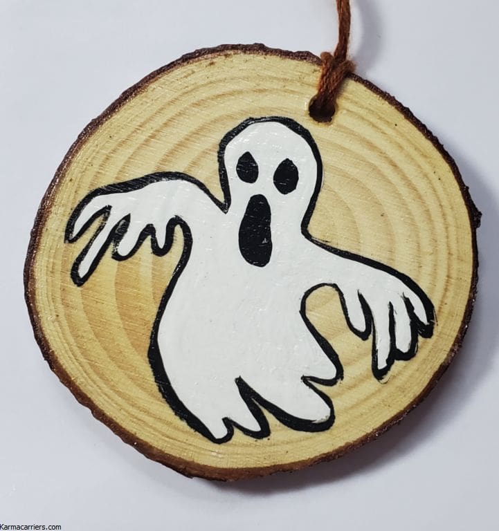 A wooden disc with a ghost painted on it.