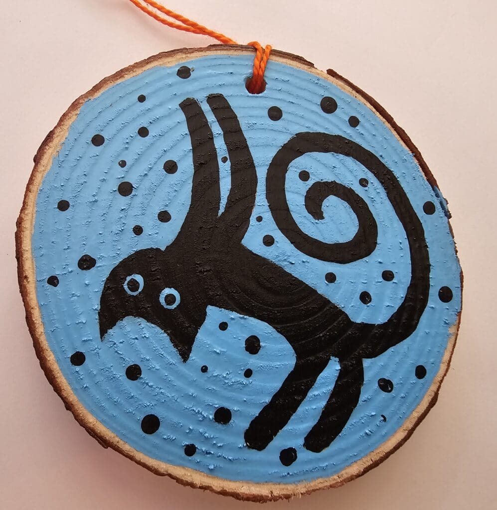 A wooden disc with a painting of a cat on it.