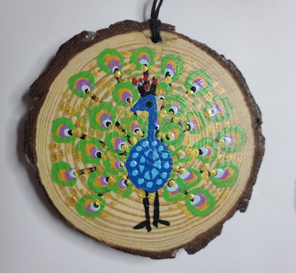 A peacock painted on wood slice with string.