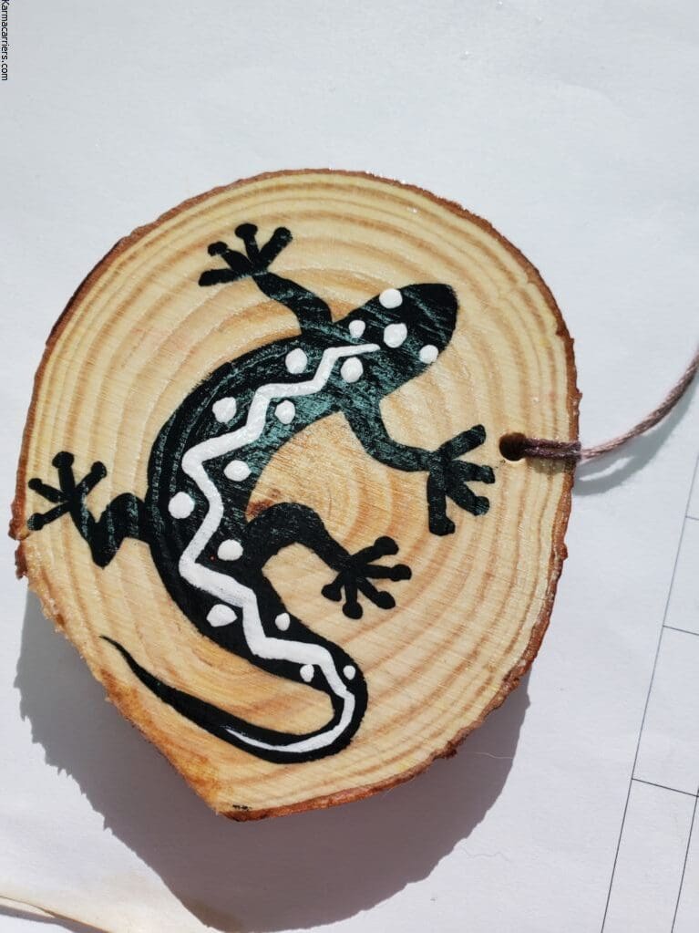 A lizard painted on wood slice with string.