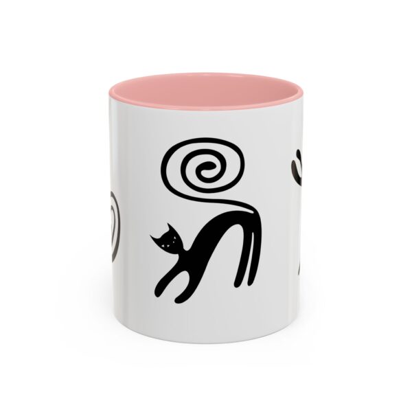 A pink and white coffee mug with black cats on it.