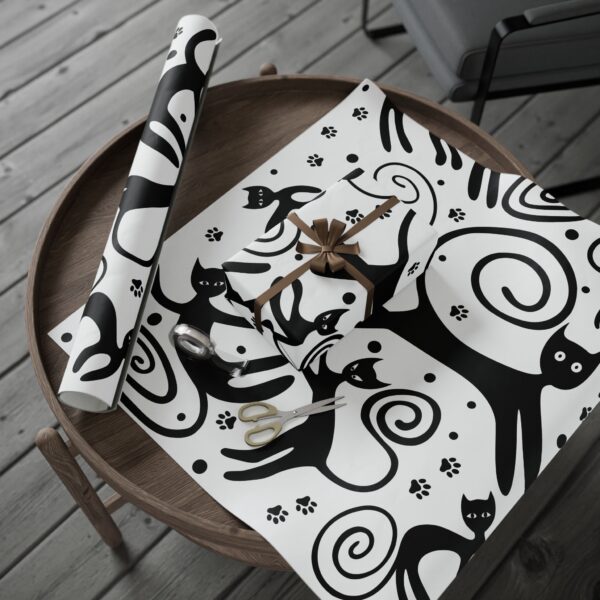 A black and white cat wrapping paper on top of a table.