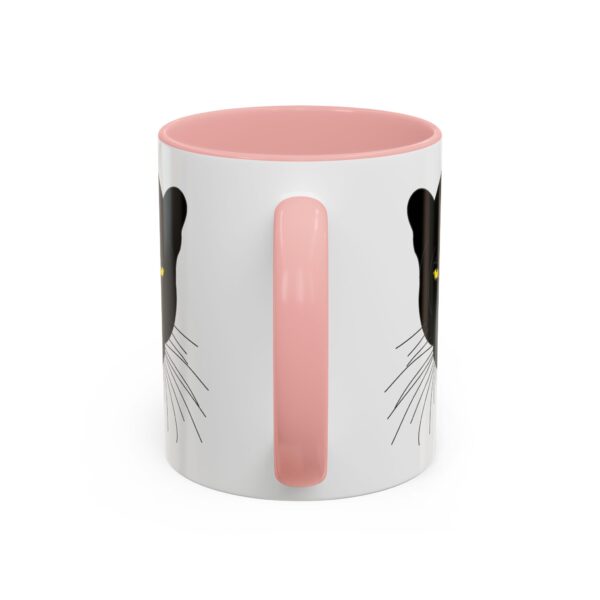 A pink and white mug with a cat face on it.