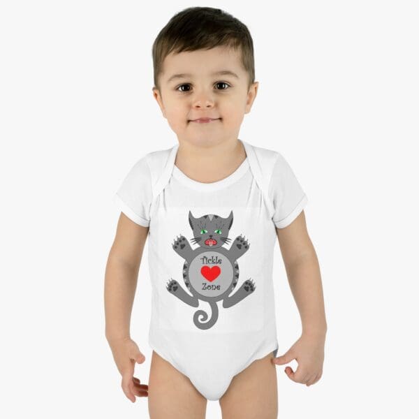 A baby wearing a white onesie with a cat on it.