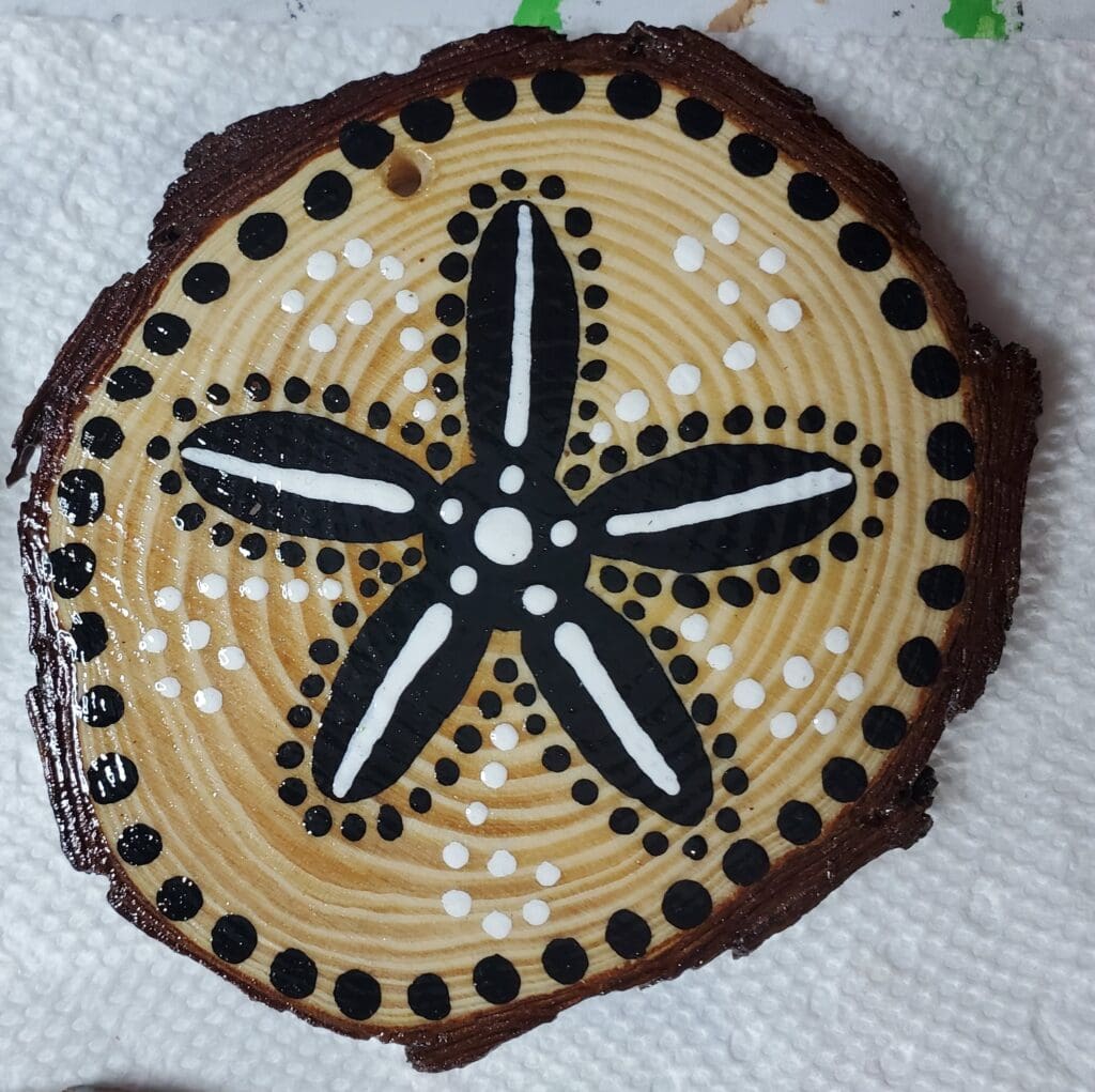 A wooden slice with a black and white design on it.