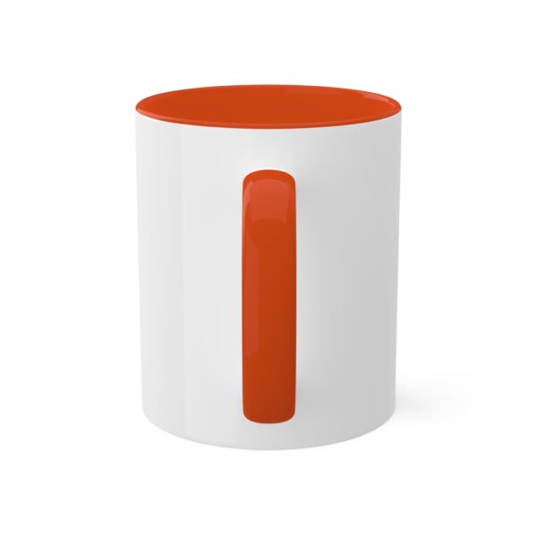 A white mug with an orange handle on top of it.