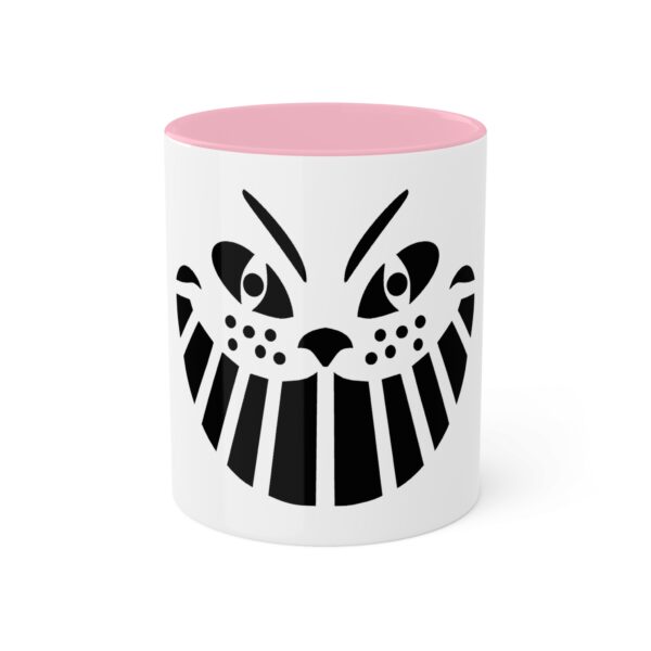 A pink and white mug with an image of a cat 's face.