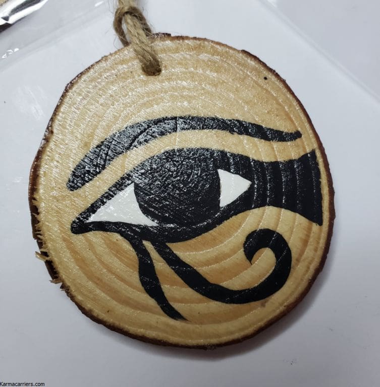 A wooden keychain with an eye of horus painted on it.