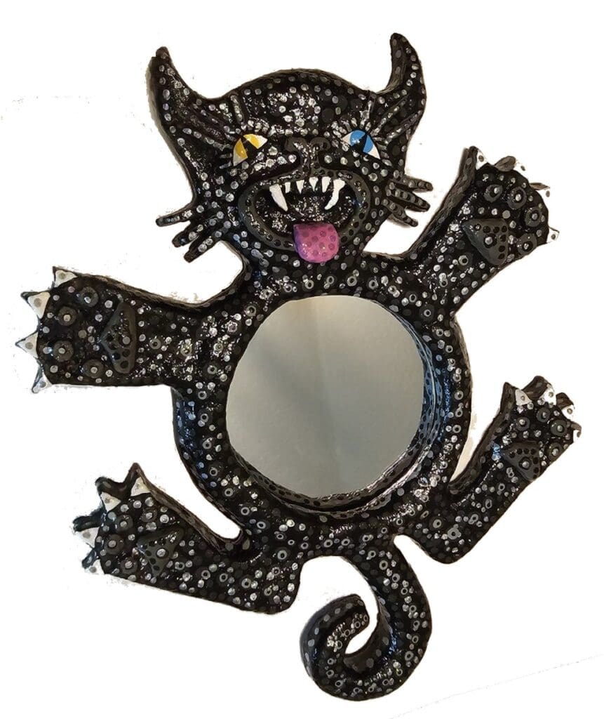 A black cat with yellow eyes and teeth is holding a mirror.