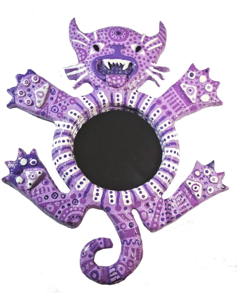 A purple cat mirror with white designs on it.