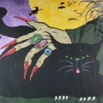 Witch's hand with rings petting a black cat.