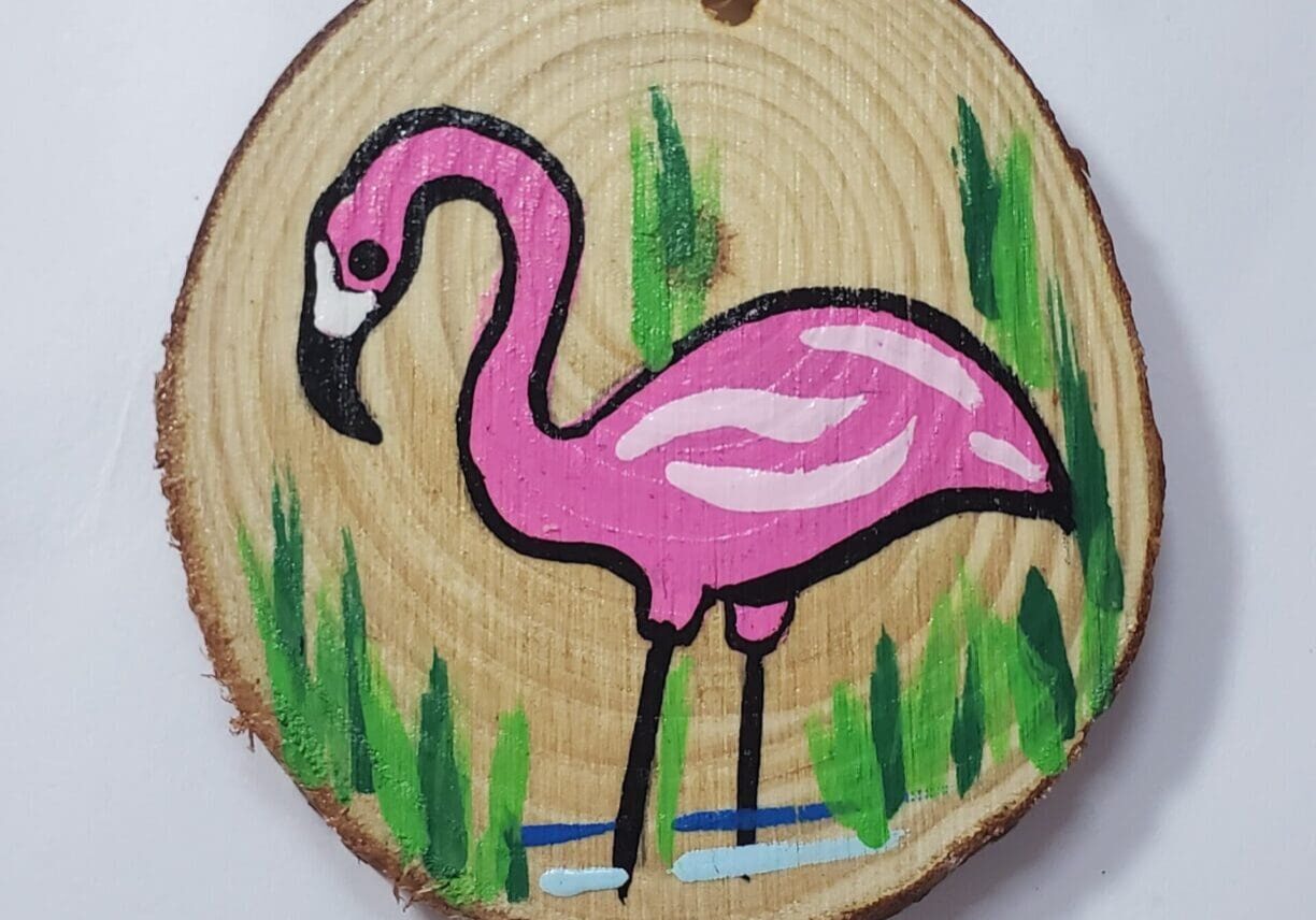 A pink flamingo painted on wood slice.