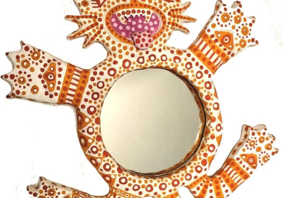 A mirror with an orange cat on it's back.